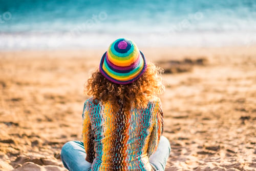 Preview: Rear view of lonely woman sitting on sand at beach. Woman relaxing peacefully while sitting