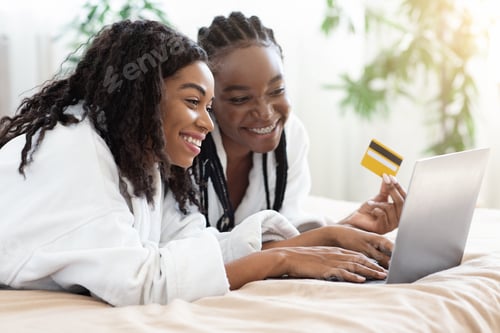 Preview: African american ladies shopping online at home, using laptop