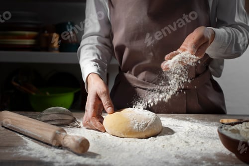 Preview: Baking concept. Caucasian female hands throwing flour at the dough.