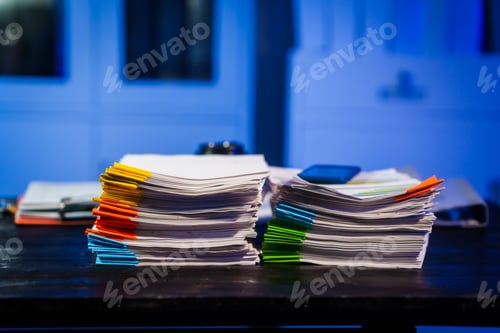 Preview: A quiet office desk at night, illuminated by a desk lamp. Documents,papers,and files are scattered