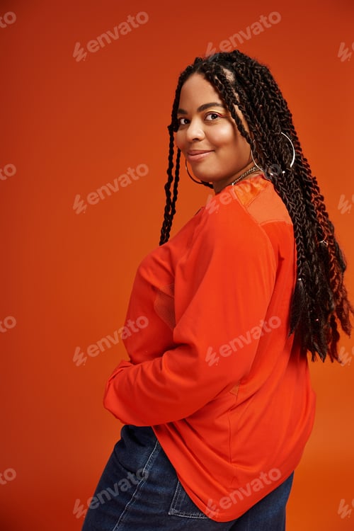 Preview: Bright casual style of a joyful woman with braids against a vivid orange backdrop
