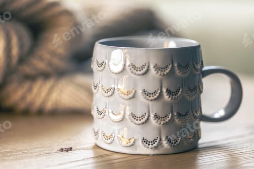 Preview: Close-up, shiny gray cup on a blurred background with a knitted element.