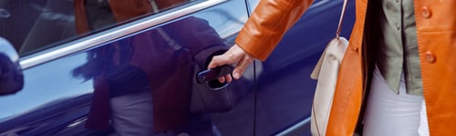 Preview: Mature woman opens door of purple car standing on city street closeup