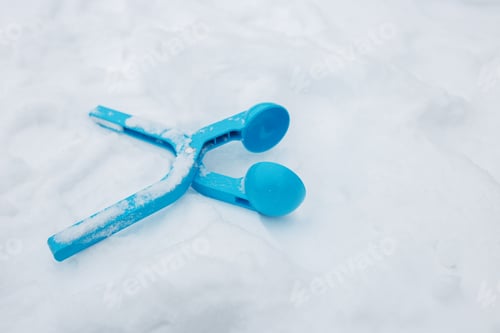 Preview: A bright blue snow shovel lies on a snowy ground during a winter day in a quiet neighborhood