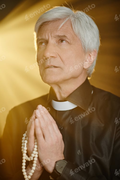 Preview: Vertical white haired senior priest praying with golden god rays