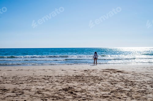 Preview: Rear view of a lonely woman standing at seashore wearing panties in sunny day