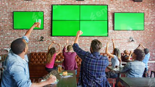 Preview: People Sitting At Tables In Sports Bar Watching Game On Green Screens And Celebrating