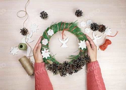 Preview: Woman making Christmas wreath and decorating it salt dough stars and angels