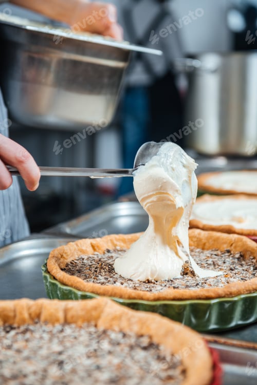 Preview: Chief cook in process of cooking several pies with cream