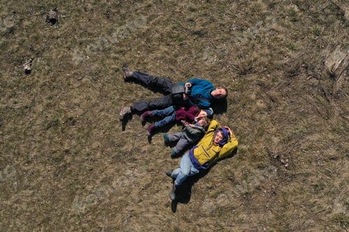 Preview: Aerial Drone View of a Happy Family with Mom, Dad and Two Kids Laying in the Grass