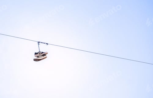 Preview: Shoe tossing Old Shoes tangled hanging on electric wire against sky