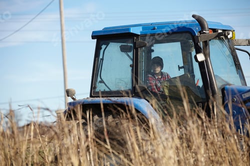 Preview: Boy farmer driving tractor in dairy farm field