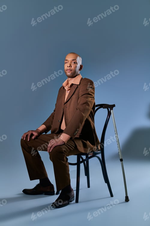 Preview: Man Poses Elegantly in Brown Suit on Chair