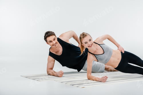 Preview: young beautiful couple doing side plank isolated on white