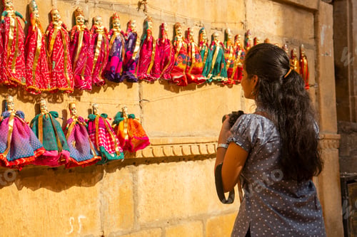 Preview: Woman tourist taking photos of puppets on the street of Jaisalmer, India.