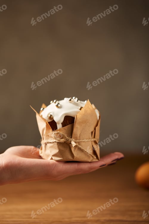 Preview: cropped view of woman holding traditional easter cake decorated with frosting and sprinkles