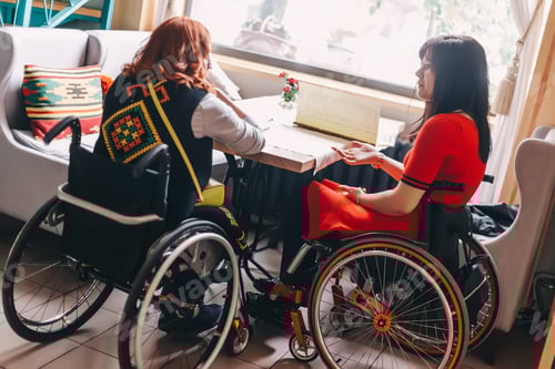 Preview: Two girls in wheelchairs in a cozy cafe waiting for an order.