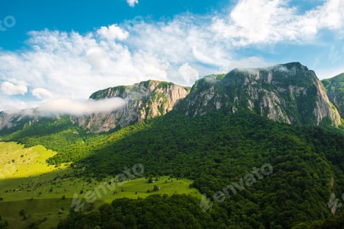 Preview: Rocky mountain range with trees and clouds