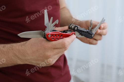 Preview: Man holding multitool on light background, closeup
