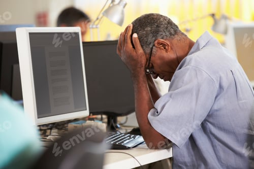Preview: Stressed Man Working At Desk In Busy Creative Office