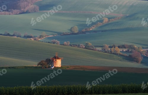 Preview: Majestic landscape of field in the evening. Windmill in the center of meadow