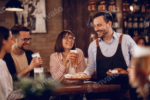 Preview: Happy waiter serving food to group of friends in a pub.