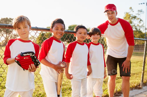 Preview: Coach and young boys in a baseball team looking to camera