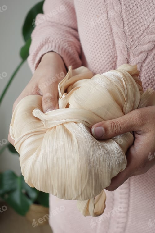 Preview: Hands hold soft fabric in a cozy indoor setting