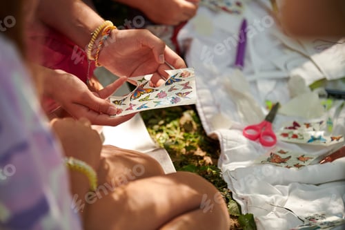 Preview: Children paper crafting with parents in outdoor children party, painting stickers and making figures