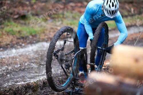 Preview: Cyclist wearing bicycle helmet repairs upside down bicycle