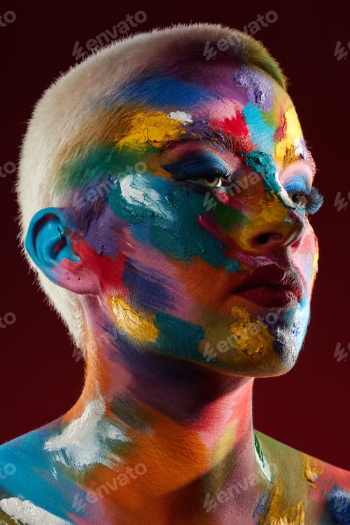 Preview: Studio shot of a young woman posing with multi-coloured paint on her face