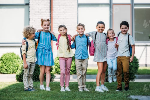 Preview: group of adorable schoolchildren standing at school garden and looking at camera