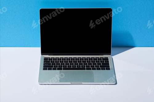 Preview: laptop with blank screen on white desk and blue background