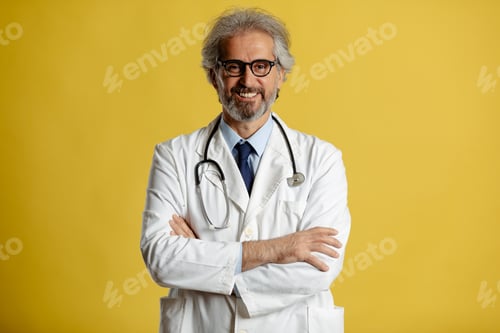 Preview: Portrait of senior doctor with eyeglasses and stethoscope standing and posing on yellow background.