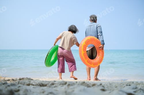 Vista previa: Senior couple holding hands while standing in shallow sea water