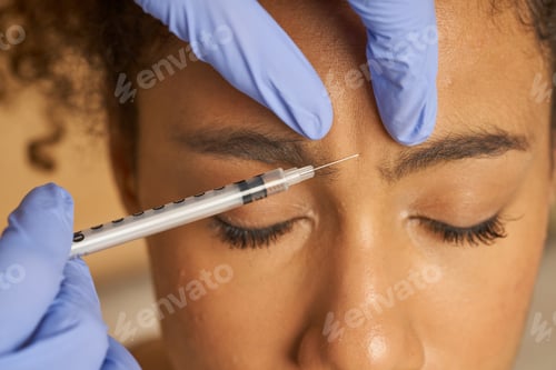 Preview: Close up shot of cosmetic injection to the pretty young female face isolated over beige background