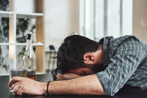 Preview: Drunkenness is temporary suicide. Alcohol abuse: drunk man lying down on a table with glass of