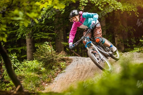 Preview: Young female mountain biker jumping on forest track