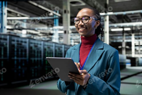 Preview: Cheerful data center female technician uses tablet to do maintenance tasks