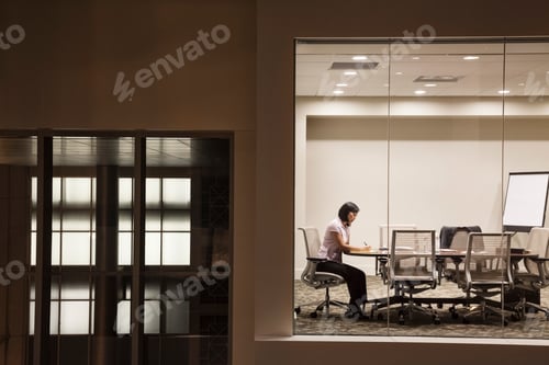 Preview: A view looking into a conference room at night of an Asian businesswoman.