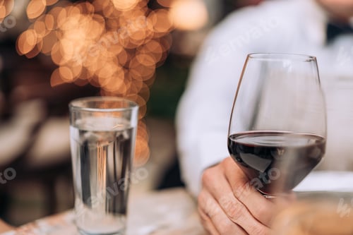 Preview: Man having wine at dinner in a restaurant with a glass of water