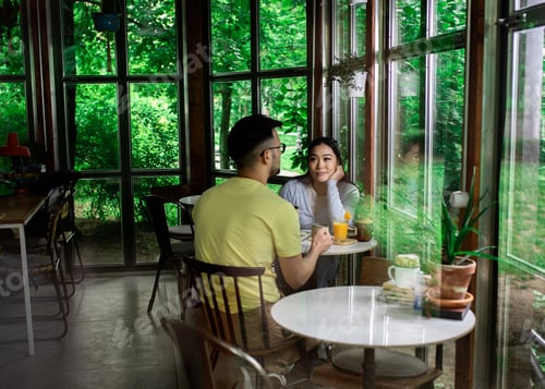 Preview: Couple sitting in a coffee shop talking and drinking coffee.