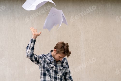 Preview: young stressed man throw crumpled paper files in the air, freedom concepts