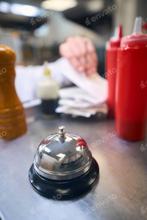 Preview: Shiny metal bell on a rack in a restaurant kitchen
