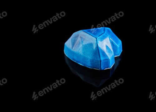 Preview: Chocolates in the form of precious stones - sapphire in the shape of a heart on a black background.