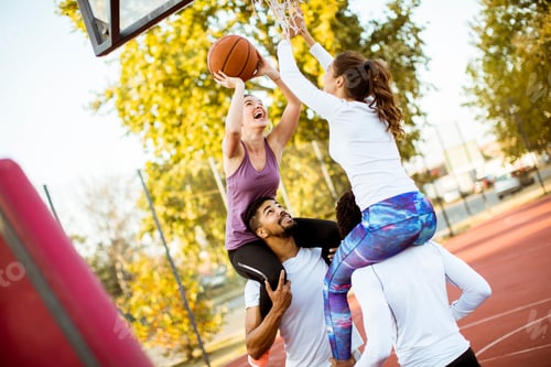 Preview: Group of multiethnic people playing basketball on court