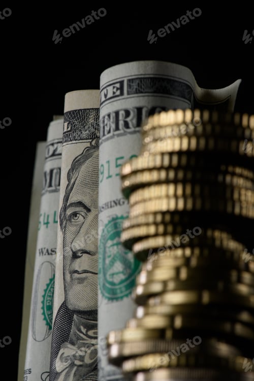Preview: selective focus of rolled dollar banknotes and pile of coins isolated on black
