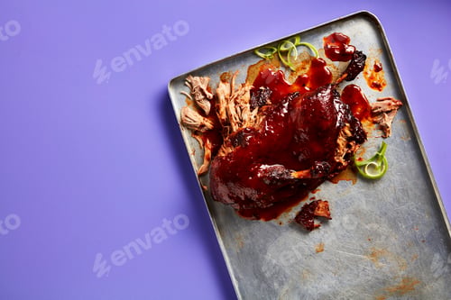 Preview: Savory pulled pork with barbecue sauce on a metal tray against a purple background