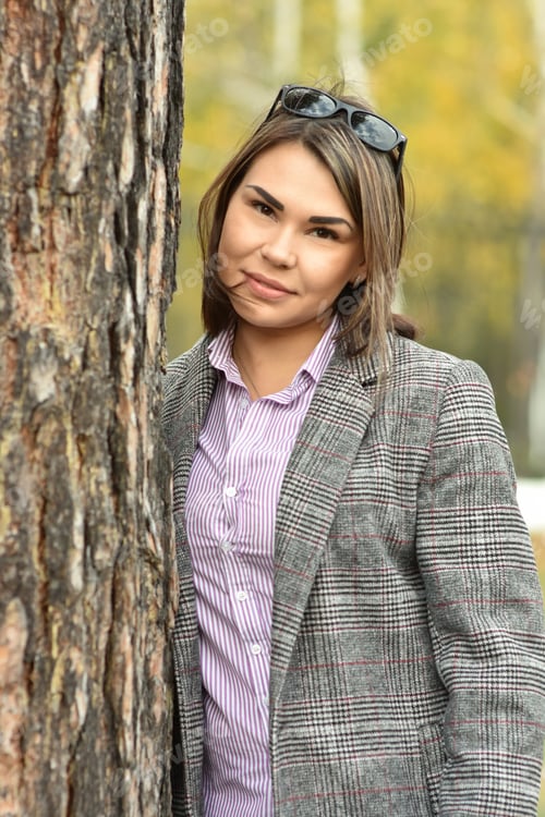 Preview: Young business woman walks in the park in autumn and smiles.