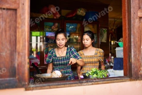 Preview: thai mother cooking together with teen daughter in rustic kitchen